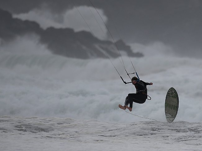 A kite surfer enjoys the stormy seas at Fistral Beach in Newquay, Cornwall.