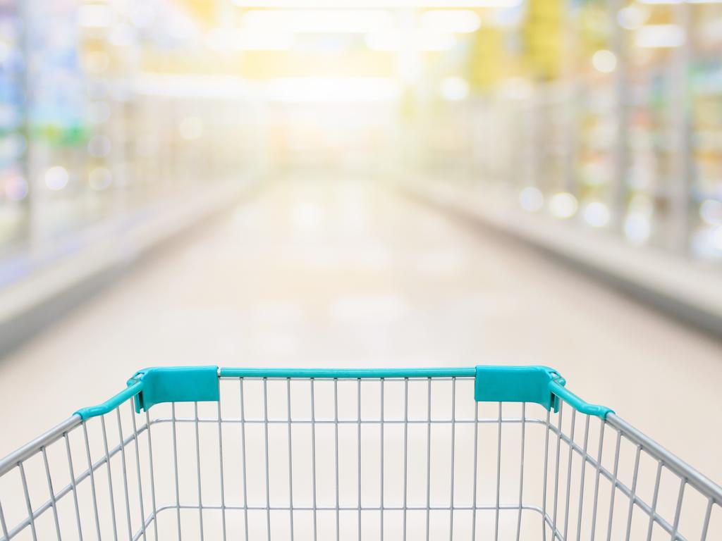 Shopping cart view with milk and yoghurt product shelves aisle in supermarket