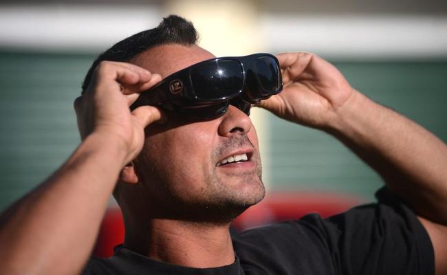 Joe Murphy, of Currumbin, looks through six pairs of sunglasses to view the eclipse. Picture: John Gass