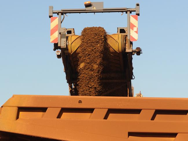 An earth mover receives iron ore from a surface miner in the mine pit at Fortescue Metals Group Ltd.'s Cloudbreak operation in the Pilbara region of Western Australia, on Monday, July 25, 2011. Fortescue Metals Group, Australia's third-biggest producer of iron ore, will release their full-year earnings on August 19. Photographer: Carla Gottgens/Bloomberg