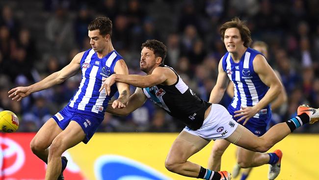 Jy Simpkin of the Kangaroos kicks while being tackled by Travis Boak of the Power. Picture: Getty Images