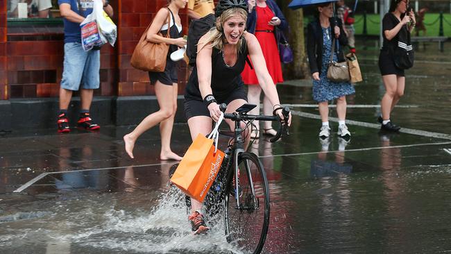 A cyclist pedals through the water at Flinders Street. Picture: Ian Currie