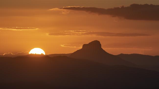 Wollumbin {Mt Warning} at sunset. It has traditional significance to the local Bundjalung people. The local Aboriginal name for the mountain is "Wollumbin"; meaning, "cloud-catcher", or alternatively "fighting chief of the mountains". The mountain's English name was bestowed on it by Lieutenant James Cook in May 1770, as his expedition in command of the Endeavour passed it by on their route northwards along the eastern coastline of Australia. The designation "Mount Warning" was meant to indicate the danger of the offshore reefs they encountered.  The Park is part of the Shield Volcano Group of the World Heritage Site Gondwana Rainforests of Australia inscribed in 1986 and added to the Australian National Heritage List in 2007. It is in NSW but this view is from the Lamington National Park in Queensland. It is part of the Border Ranges Caldera.