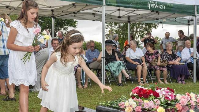 SOLEMN CEREMONY: Rose Robinson and Sophie Griffin lay flowers at the Babies of Walloon grave dedication. Picture: Lyle Radford