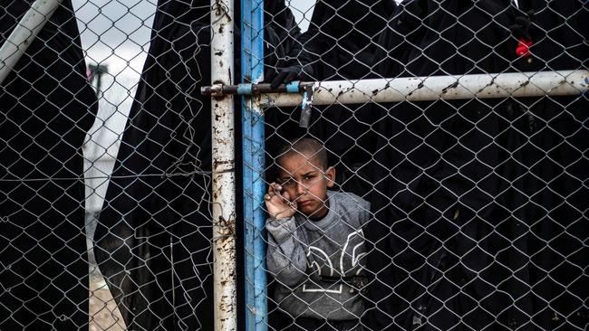 A child waits behind a wire fence door in al-Howl camp, which houses relatives of Islamic State group members, in al-Hasakeh, northeastern Syria. Picture: AFP