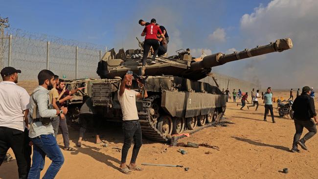 Palestinians take control of an Israeli Merkava battle tank after crossing the border fence with Israel from Khan Yunis in the southern Gaza Strip on October 7. Picture: AFP