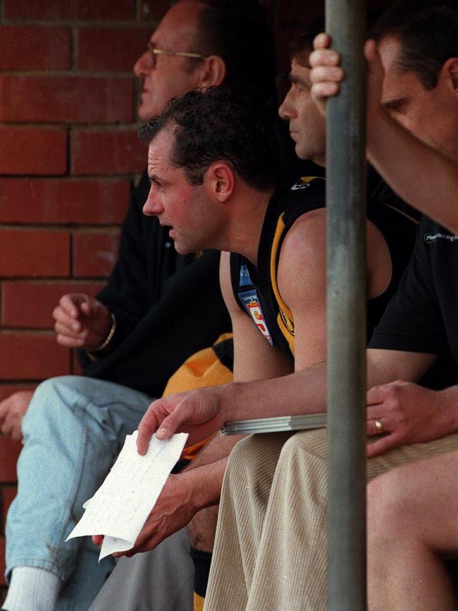 Player-coach Tony McGuinness watches from the bench at Glenelg Oval in 1998.