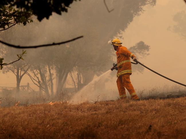 A CFS firefighter battles a fire as it runs across a paddock near a home on Ridge Road at Woodside in the Adelaide Hills in Adelaide, Friday, December 20, 2019. Two bushfires are burning out of control around the Adelaide Hills, prompting emergency warnings from the Country Fire Service. (AAP Image/Kelly Barnes) NO ARCHIVING