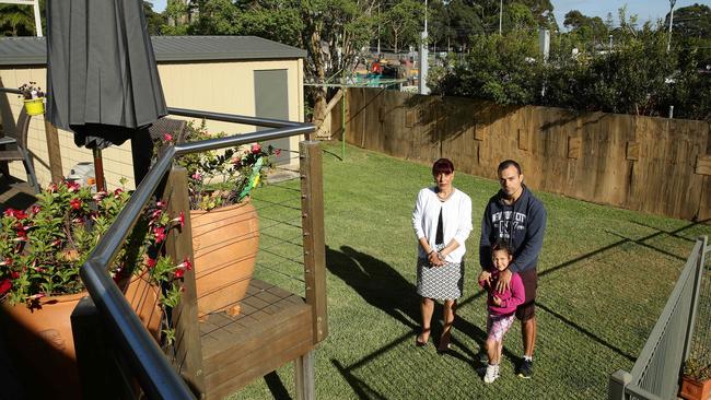 Residents of Karingal Crescent in Frenchs Forest have had parts of their backyards taken away. Barbara Schiliro and Tim Pace with daughter Willow, five, in Barbara's backyard.