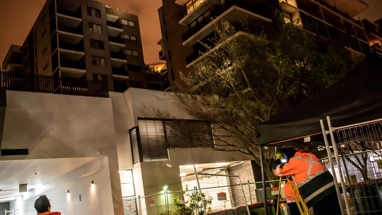 Workers outside the cracking Mascot Towers on Monday night. Picture: Monique Harmer