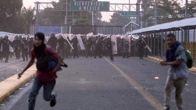 Central American migrants run from Mexican authorities during clashes on a border bridge that connects Guatemala and Mexico. Picture: Billy Santiago/AP