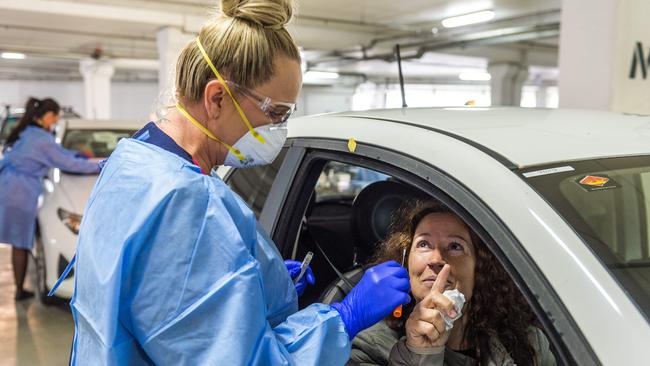 Bunnings car park in West Footscray is being used for coronavirus testing. A worker prepares to swab test Linda Telai. Picture: Jake Nowakowski