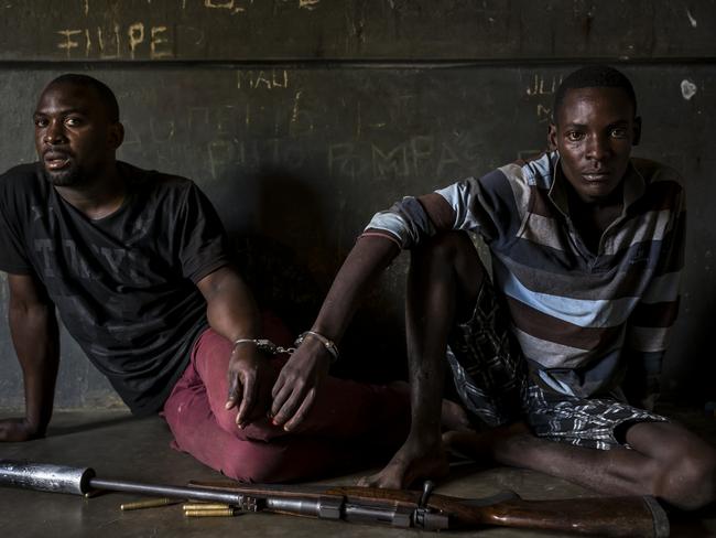Nature - First Prize, Stories © Brent Stirton, Getty Images for National Geographic Magazine Two rhino poachers, one 19, the other 28 years old, apprehended by an anti-poaching team in Mozambique close to Kruger National Park border. They are seen waiting to be processed in the local jail. After a three-day chase, they were caught in a roadblock and the rifle seized shortly thereafter. This was due to a coordinated effort between Kruger National Park in South Africa where the poachers intended to shoot rhino for their horn; and Sabi Game Park, a conservancy on the Mozambique side. The poachers were tracked and identified by their unique shoe pattern.