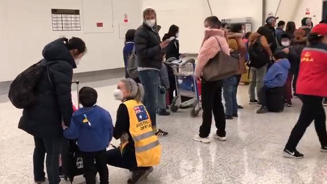 An official helps Australian citizens and permanent residents as they board a Qantas flight in Wuhan on Monday.