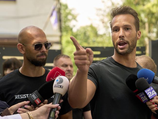 Andrew Tate, left, watches his brother Tristan speak, outside a police station in Voluntari, Romania in May. Picture: AP Photo