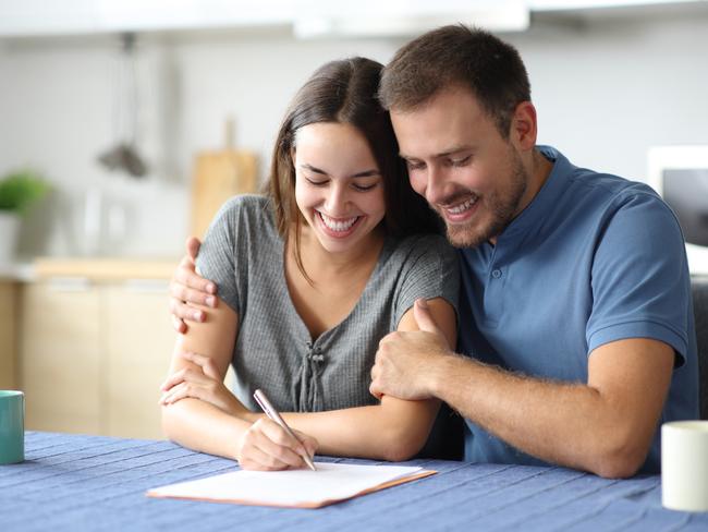 Happy couple signing document at home; list of life goals generic