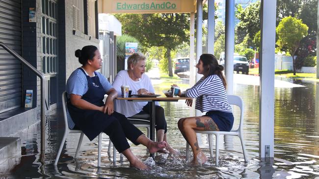 Bumbles staff enjoy "a little bit of Venice" in the floodwater at Budds beach as it is inundated by the high tide. Left to right they are Solofa Fatu, Kate Madison (owner) and Sofia Soroa. Picture: Glenn Hampson .