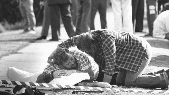 Distraught bikie Phillip Bull Campbell is consoled by a mate as he lays over the body of his brother Greg Shadow Campbell, who was shot dead in the battle between members of the Comencheros and Bandidos bikie gangs at the Viking Tavern, Milperra.