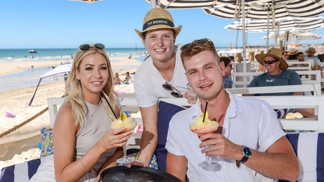 Alice Skocz and Jon Dawson of West Beach enjoying a drink on the sand at the Moseley Beach Club with concierge Olivia Ley. The Beach Club will be open until 6pm on NYE. Pic: Brenton Edwards.