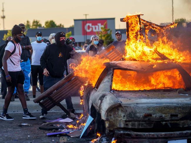 Protesters throw objects onto a burning car outside a Target store near the Third Police Precinct in Minneapolis, Minnesota, during a demonstration over George Floyd’s death. Picture: AFP