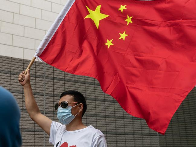 HONG KONG, CHINA - APRIL 16: A pro-China supporter waves a Chinese flag outside the West Kowloon Magistrates Courts to celebrate the sentencing of the pro-democracy activists on trial on April 16, 2021 in Hong Kong, China. Seven prominent democratic figures, including Apple Daily founder Jimmy Lai, former lawmaker and barrister Martin Lee and Margaret Ng, were convicted of unauthorized assembly in relation to a peaceful protest on August 18, 2019. (Photo by Anthony Kwan/Getty Images)