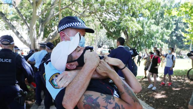 A protester is restrained by a police officer duirng today’s rally. Picture: Richard Dobson