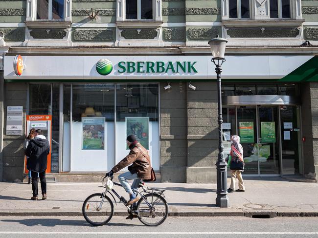 A man cycles past one of the Slovenian branches of the Russian state-owned bank Sberbank, in Ljubljana on February 28, 2022. - The ruble collapsed against the dollar and the euro on the Moscow Stock Exchange on February 28, 2022, as the West punished Moscow with harsh new sanctions over the Kremlin's invasion of Ukraine. President Vladimir Putin raged against the West as he convened a meeting with officials including central bank chief Elvira Nabiullina and the CEO of Russia's largest lender Sberbank, German Gref, to address what the Kremlin called a new "economic reality". (Photo by Jure Makovec / AFP)