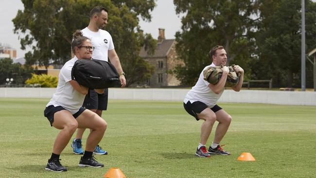 AFLW star Emma Kearney teaches Herald Sun reporter Sam Landsberger about sandbag squats.