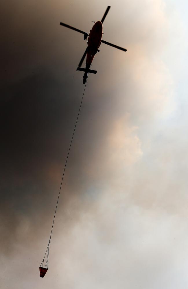 A waterbombing helicopter targeting a blaze behind houses. Picture: Peter Lorimer