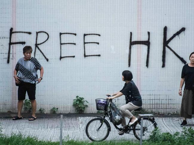 A cyclist rides past graffiti that reads "Free HK" in the Tai Wai area of Hong Kong on August 10, 2019, as protesters take part in demonstrations against a controversial extradition bill. - Police in Hong Kong fired tear gas on August 10, 2019 at pro-democracy protesters who defied orders to cancel a rally and blocked intersections across the city in "hit-and-run" demonstrations. The new protests came after the city's leader warned she would grant no concessions to the demonstrators, whose movement is now in its third month. (Photo by Anthony WALLACE / AFP)