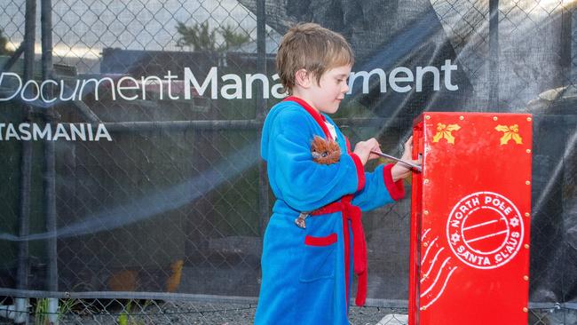 A boy posts a letter to Santa outside Document Management Tasmania in Montrose. The post box was later stolen.