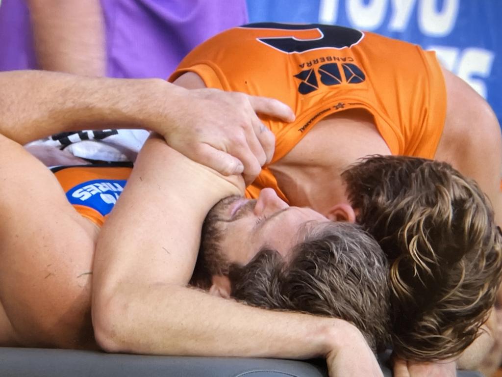 And Ward is comforted by Lachie Whitfield on the bench after the injury. Picture: Fox Footy