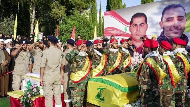 Hezbollah members stand over the coffins of a civilian and a Hezbollah fighter killed in an Iranian strike. Picture: AFP.