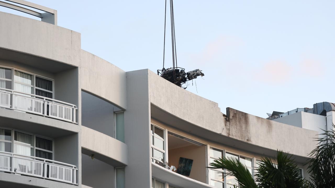 A large crane lifts the wreckage of a Robinson R44 helicopter off the roof top of the Double Tree Hilton hotel into a skip bin, before lowering it to the Cairns Esplanade. The chopper was stolen from Nautilus Aviation and crashed onto the roof at about 1:50am on Monday. Picture: Brendan Radke