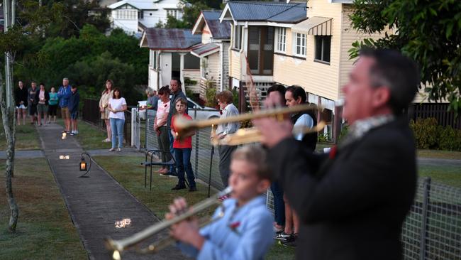 Alastair Tomkins and his nine year-old son Hugo play The Last Post in their driveway, at dawn, as neighbours stand outside their homes to commemorate Anzac Day in Brisbane, Saturday, April 25, 2019. Anzac Day is a national day of remembrance to commemorate the service and sacrifice of Australian and New Zealand service men and women. Due to COVID-19 restrictions marches and commemorative services have been banned for the first time in more than a century. (AAP Image/Dan Peled) NO ARCHIVING