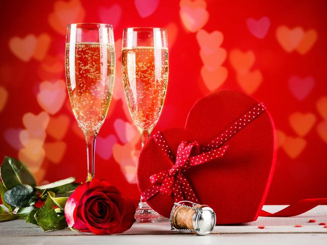 Background of Valentines day celebration with champagne, rose, heart shaped present and red candies.