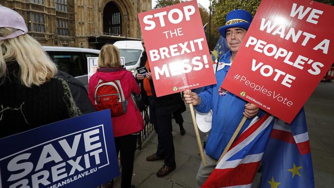 Pro and anti Brexit protesters with their placards, mingle outside the Palace of Westminster in central London.