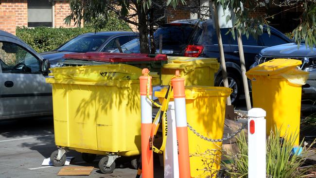 Rubbish bins containing infectious waste bags sit in the car park at the Cumberland Manor aged care home at Sunshine North. Picture: Andrew Henshaw