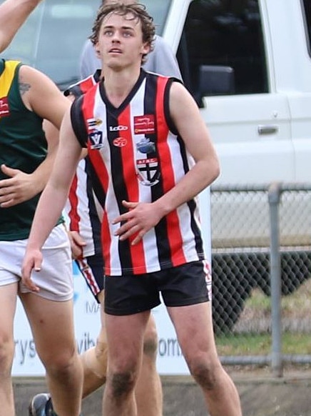 He looks up during a footy game, the ball above his head.