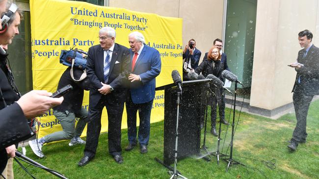 Senator Brian Burston and businessman Clive Palmer leave their press conference in a hurry after a water sprinkler is turned on at Parliament House. Picture: AAP