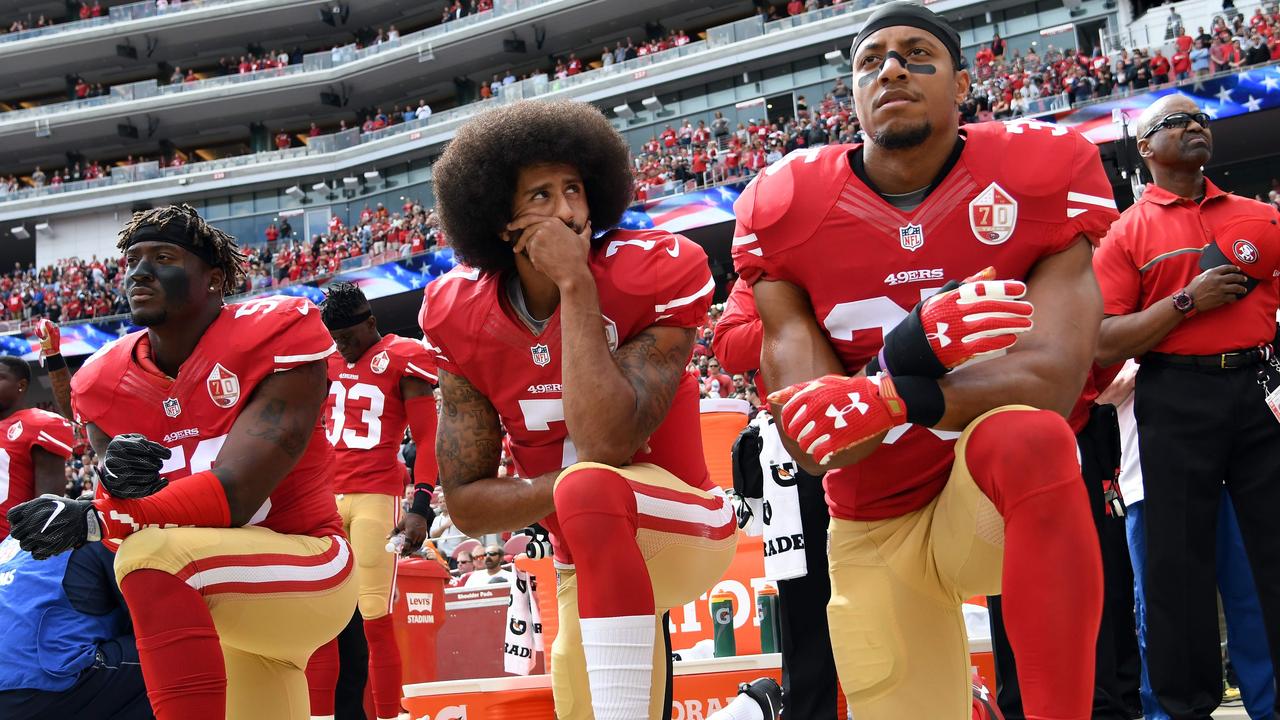 Eli Harold, Colin Kaepernick and Eric Reid kneel on the sideline during the anthem. (Photo by Thearon W. Henderson / GETTY IMAGES NORTH AMERICA / AFP)