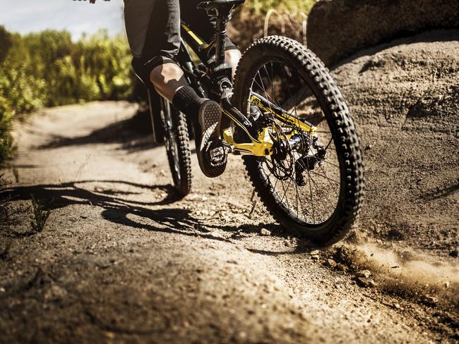 Trail riding mountain bike on a dirt road leaving dust behind and showing it's tire tread