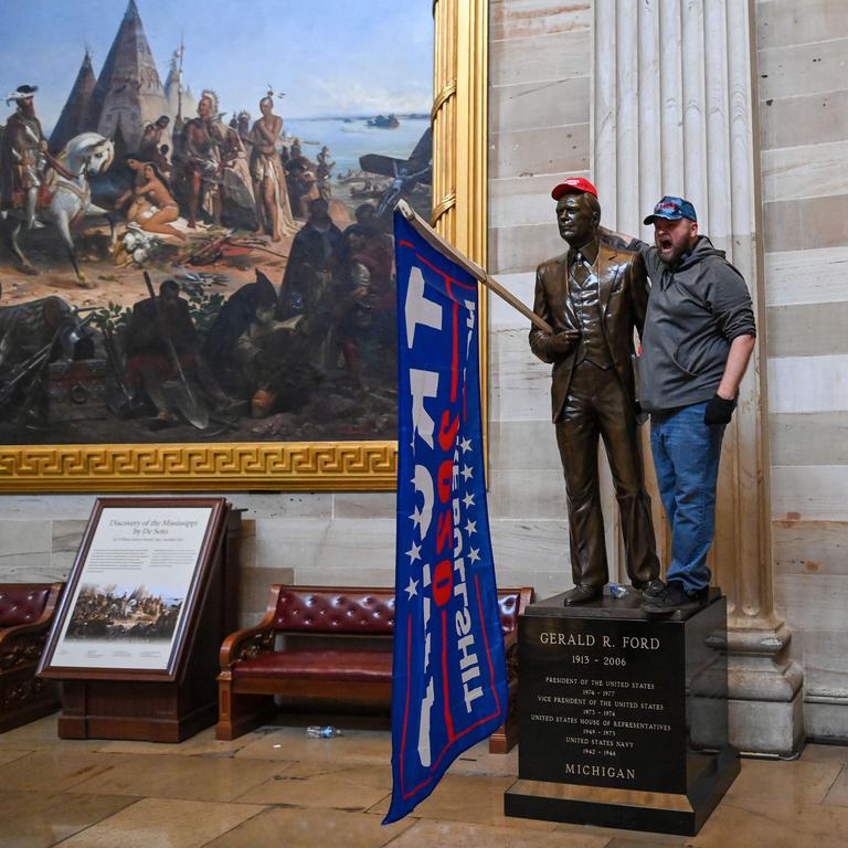 A Capitol invader poses with a statue of former President Gerald Ford that has been modified with Trump regalia. Picture: AFP