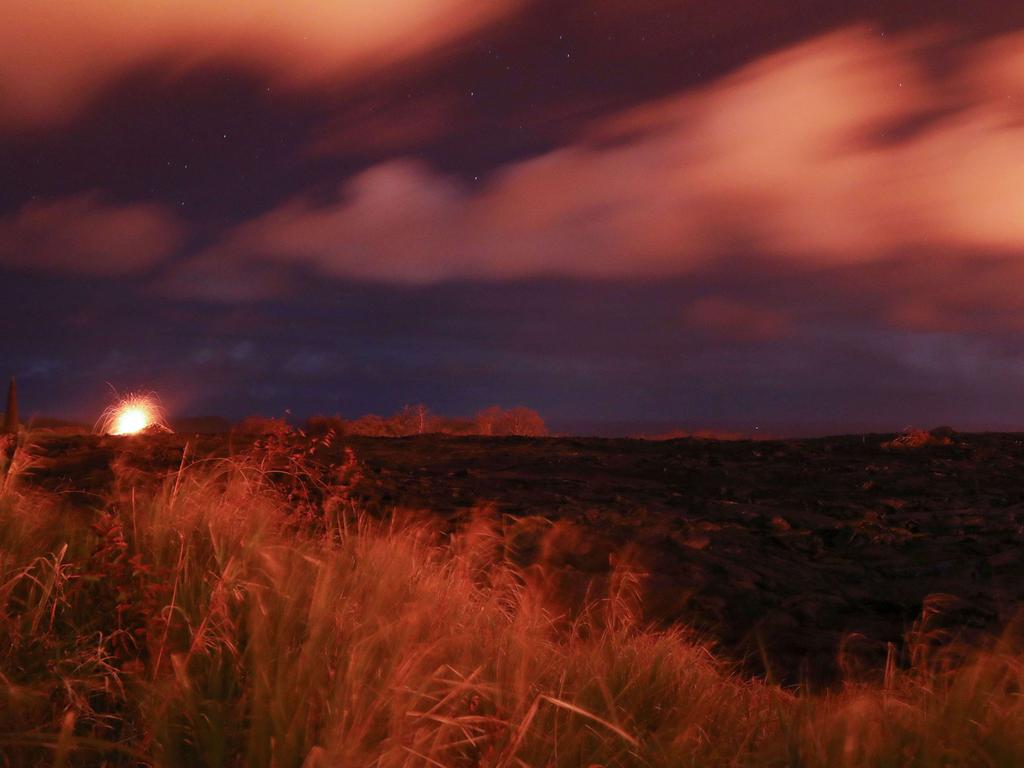 A lava fountain (L) erupts at night along a recent lava flow from a Kilauea volcano fissure on Hawaii's Big Island on May 22, 2018 in Kapoho, Hawaii. One week ago, prior to the lava flow, the area was open cow pasture. Mario Tama/Getty Images/AFP