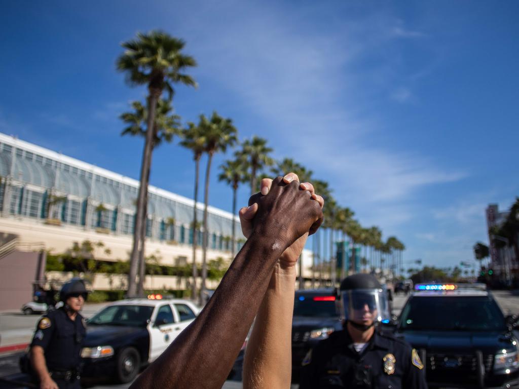 A black man and a white woman hold their hands up in a front of police officers in the protests. Picture: Apu Gomes/AFP