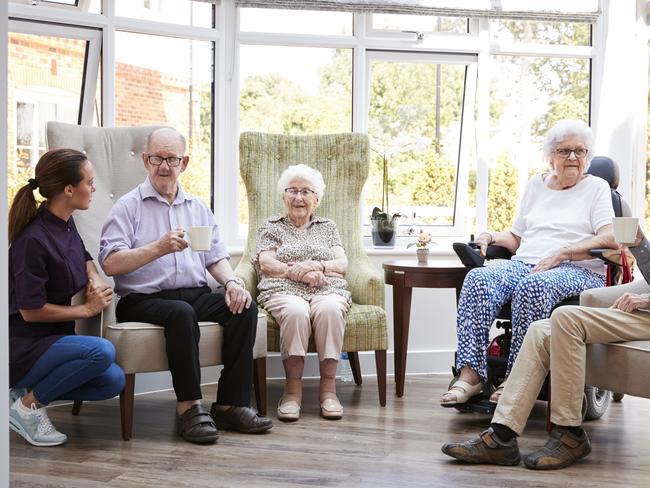 AGED CARE/NURSING HOME/SENIOR/RESIDENTIAL CARE. Picture: istock   Male And Female Residents Sitting In Chairs And Talking With Carer In Lounge Of Retirement Home