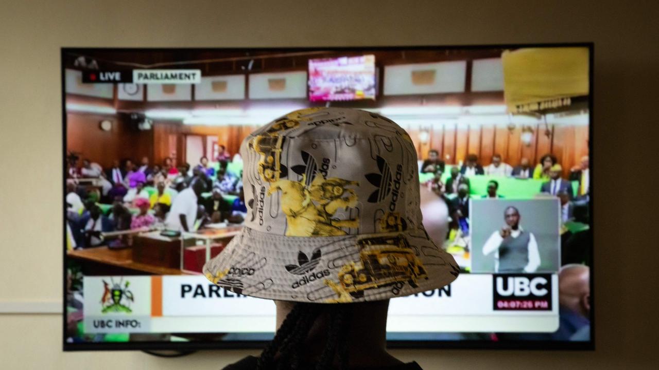 A Ugandan transgender woman who was attacked and is currently being sheltered watches parliament discuss an anti-gay bill. Picture: Stuart Tibaweswa/AFP