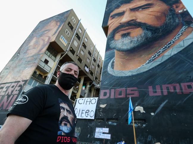 A man stands at the foot of a mural of late Argentinian football legend Diego Maradona, with the inscription in Spanish "Dios Umano" (Human God) in Italy. Picture: AFP