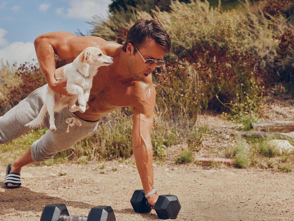 Powell does one armed push ups while holding a dog in the photoshoot, because why not? Picture: AB+DM for Men's Health