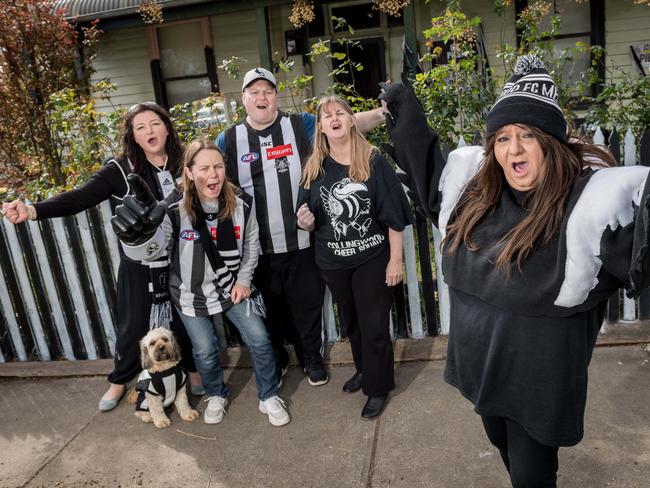 Collingwood cheer squad member Voula Bitsikas (right) paints her fence with the help of friends Dina Sarandopoulous and her dog Charli, Paige Dellamarta, Daniel Brennan and Debbie Taylor. Picture: Jake Nowakowski